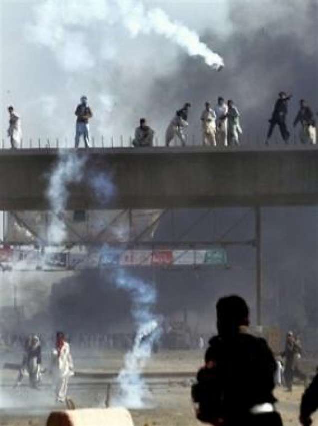 کراچی، مظاہرین پولیس کی جانب سے فائر کئے گئے آنسو گیس کے ..