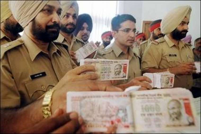 بھارتی پولیس اہلکار جعلی کرنسی نوٹ دکھا رہے ہیں، جو انکے ..