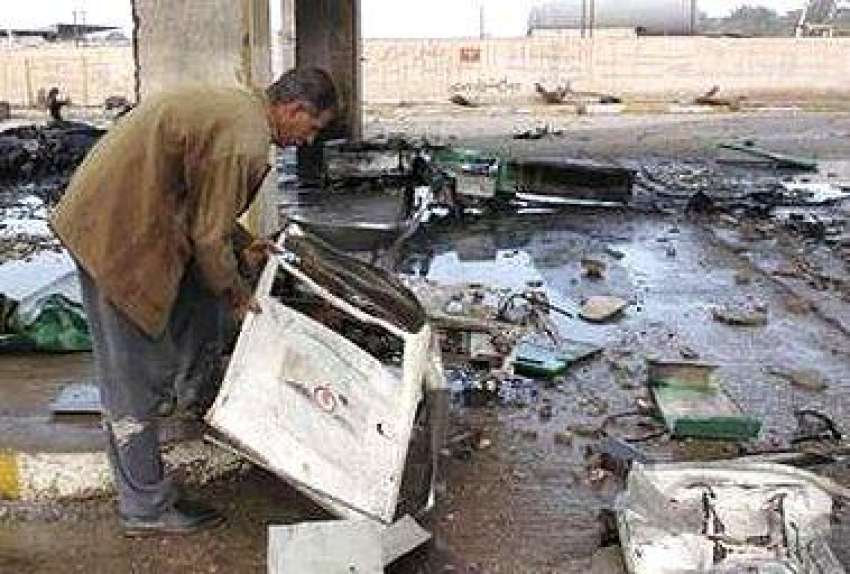 بغداد، ایک عراقی شہری بم دھماکے میں‌ تباہ ہونے والی گاڑی ..