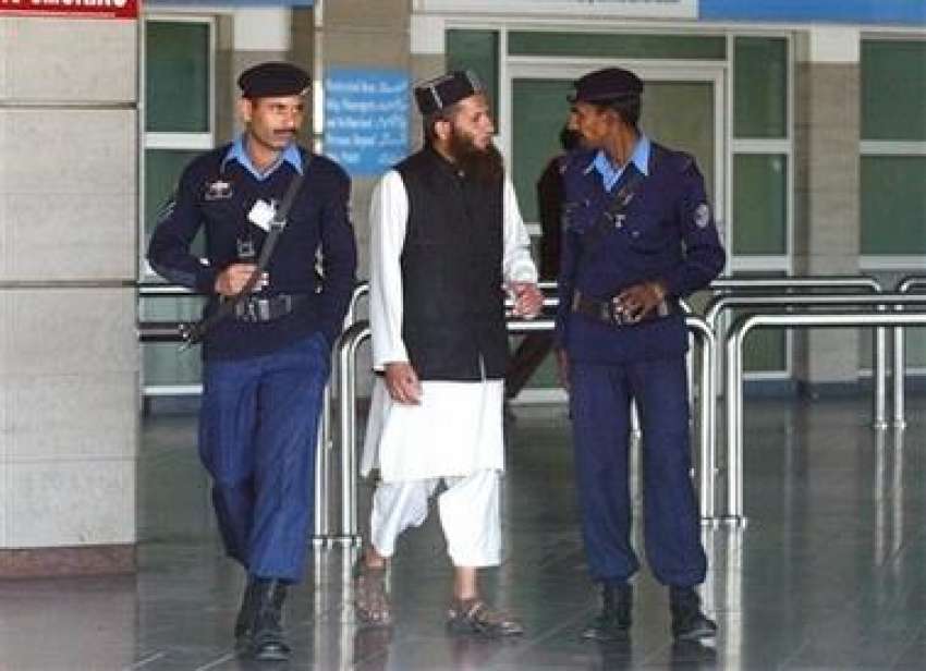 اسلام آباد، پولیس اہلکار ایک باریش شخص سے ائیرپورٹ کی لابی ..