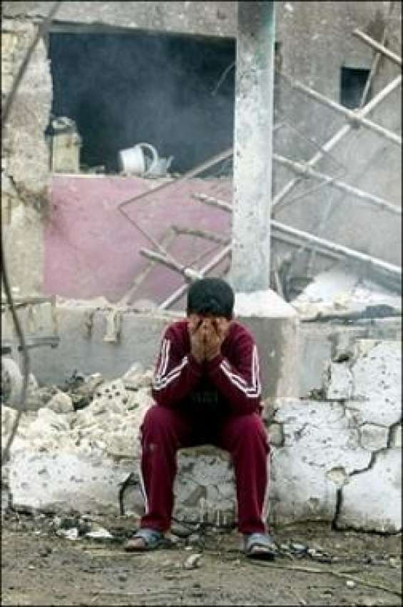 بغداد،ایک عراقی بچہ اپنے تباہ شدہ گھر کے باہر بیٹھا رو رہا ..