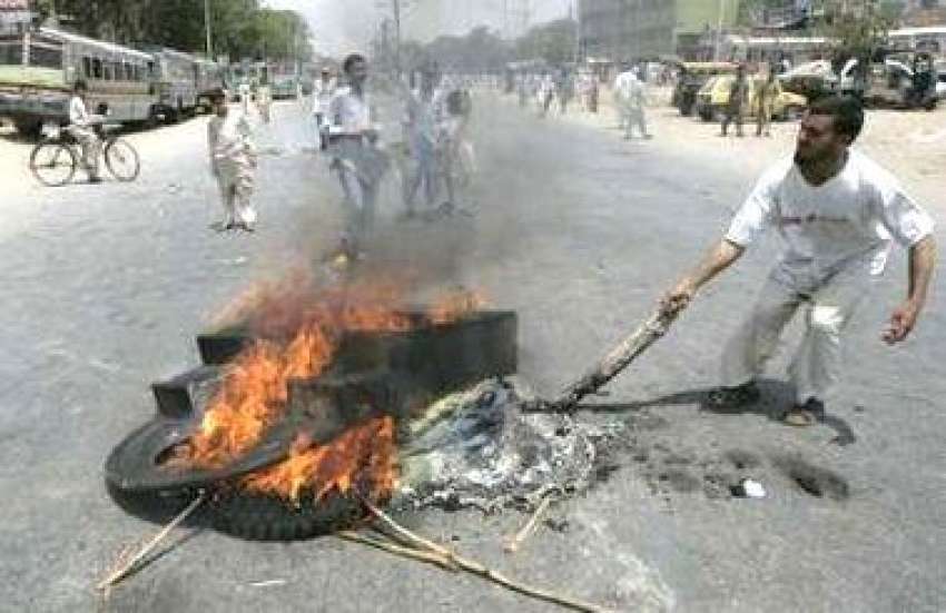 کراچی، دنگے فسادات کے دوران ایک شخص سڑک پر ٹائر جلا رہا ہے۔