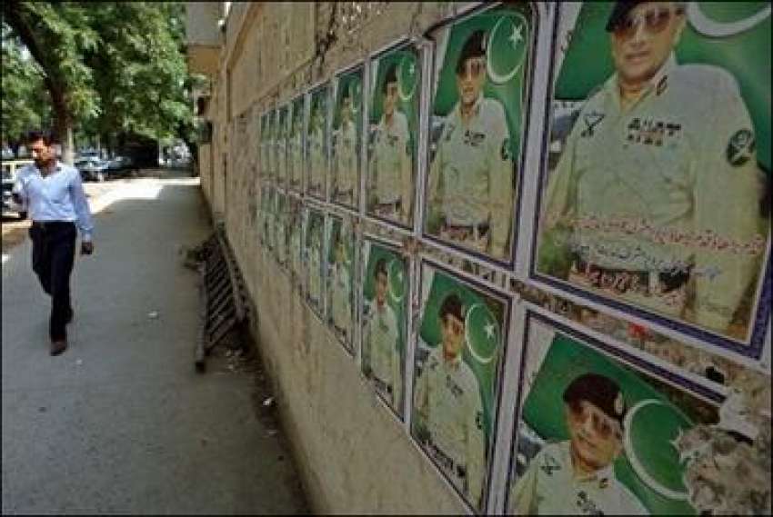 اسلام آباد،ایک شخص صدرمشرف کی پوسٹر لگی دیوار کے قریب سے ..