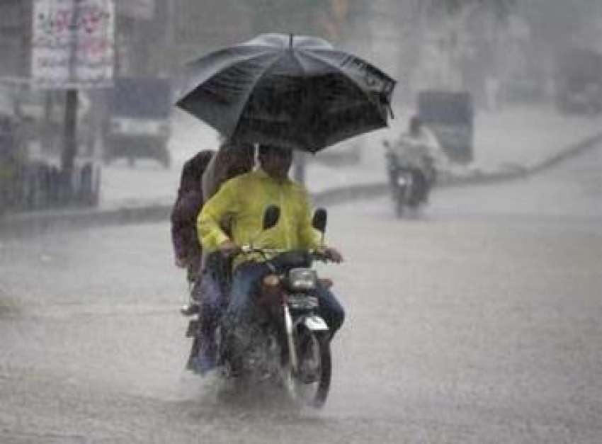 لاہور،شدید گرمی کے بعد موسلادھار بارش میں ایک موٹرسائیکل ..