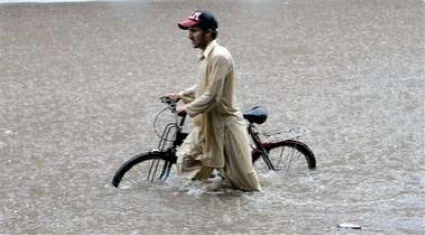 لاہور،شدید بارش میں گھٹنوں تک کھڑے پانی میں ایک سائیکل سوار ..