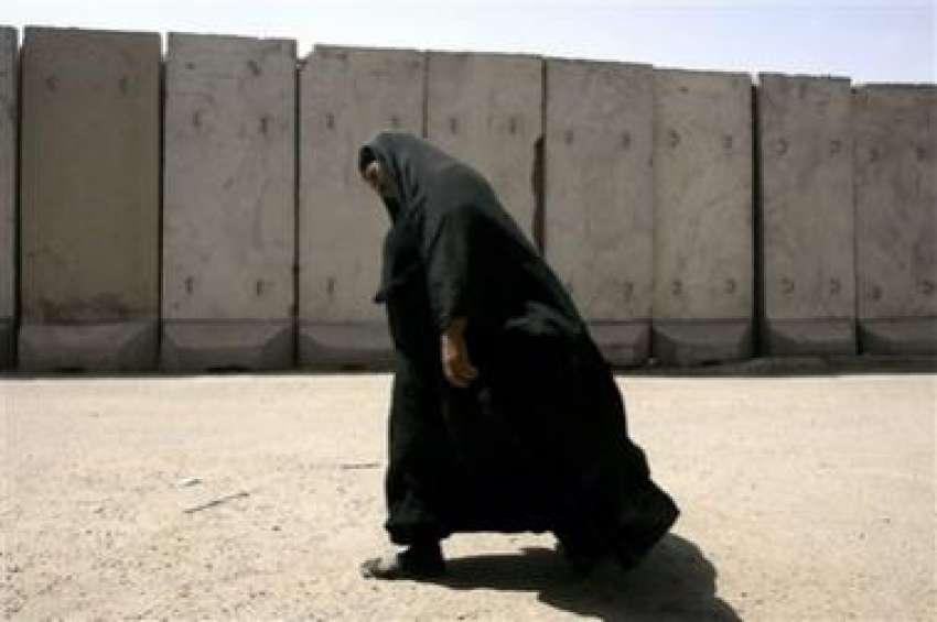 بغداد،ایک عراقی خاتون شیعہ سنی دیوار کے قریب سے گزر رہی ..