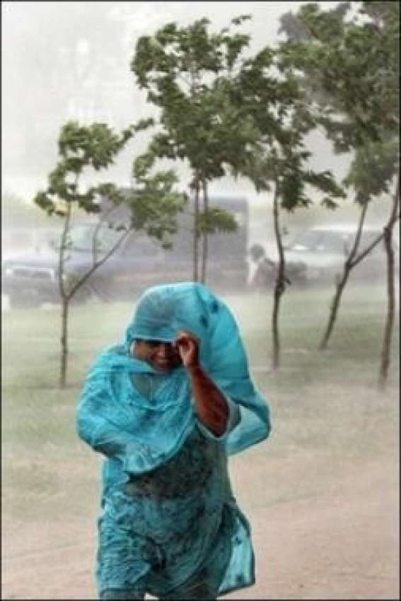 کراچی،شدید بارش میں ایک خاتون پناہ کی تلاش میں ہیں۔