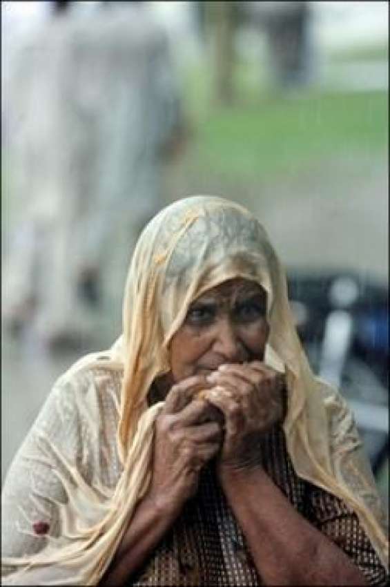 کراچی،بارش میں ایک بوڑھی خاتون بارش سے بچائو کیلئے محفوظ ..