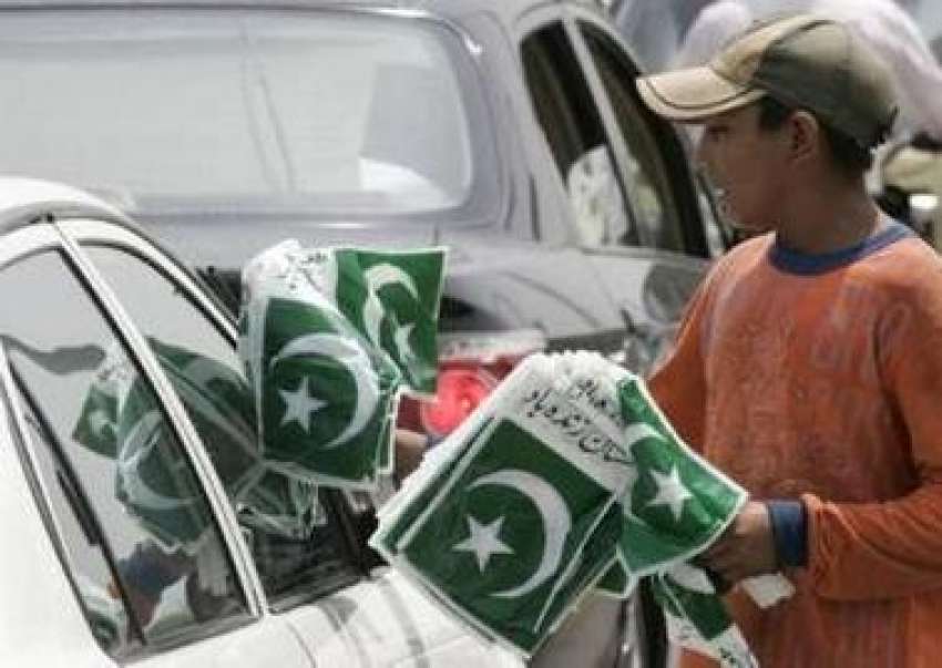 اسلام آباد،ایک بچہ ٹریفک سگنل پر پاکستانی پرچم کی جھنڈیاں ..