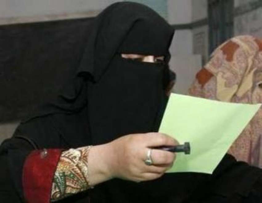 پشاور،ایک خاتون پولنگ سٹیشن میں ووٹ ڈالنے سے قبل بیلٹ  پیپر ..