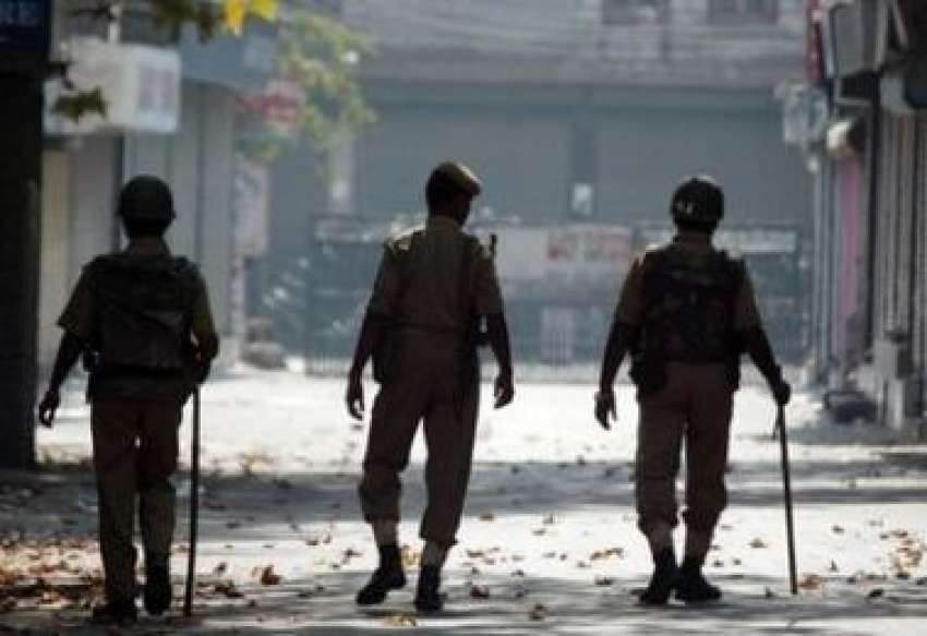 سرینگر میں کرفیو نافذ ہونے کے بعد بھارتی پولیس اہلکار سڑک ..