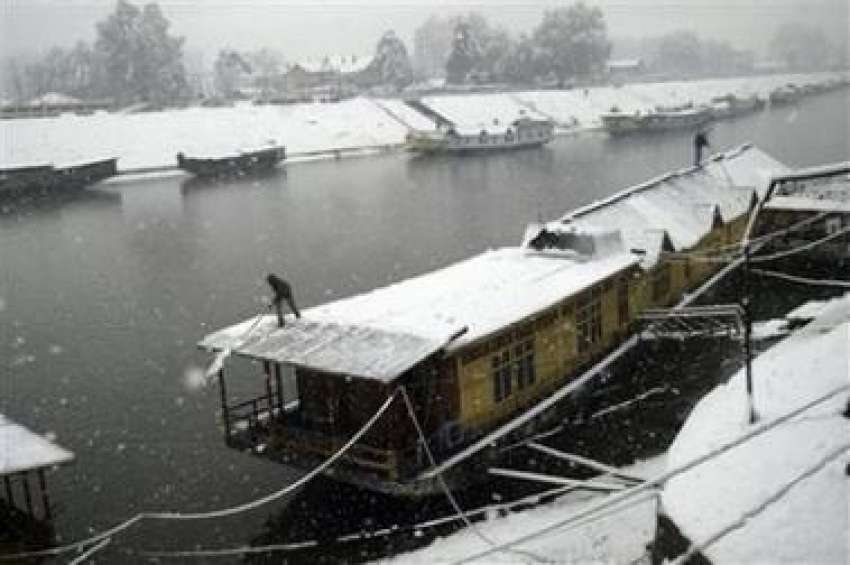 سرینگر: ایک شخص اپنی کشتی کی چھت سے موسم سرما کی پہلی برفباری ..