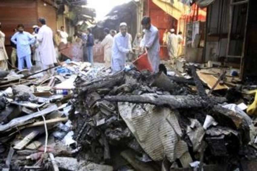 پشاور، گزشتہ روز بم دھماکے میں تباہ شدہ دکان کے ملبے سے لوگ ..