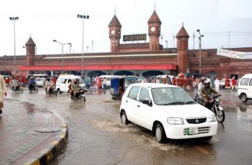 لاہور، ریلوے سٹیشن کے سامنے بارش کے کھڑے پانی میں‌ سے ٹریفک ..