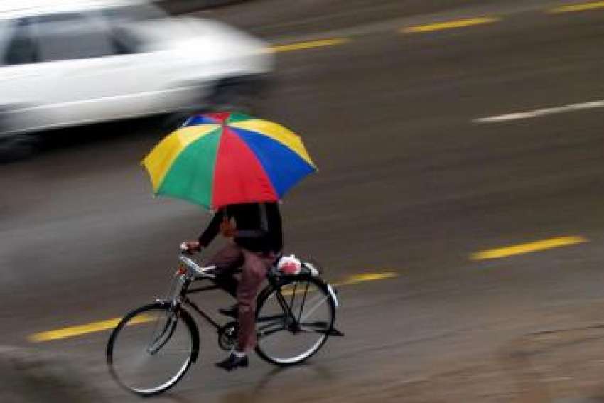 اسلام آباد، بارش کے دوران سائیکل سوار چھتری لئے منزل کی ..