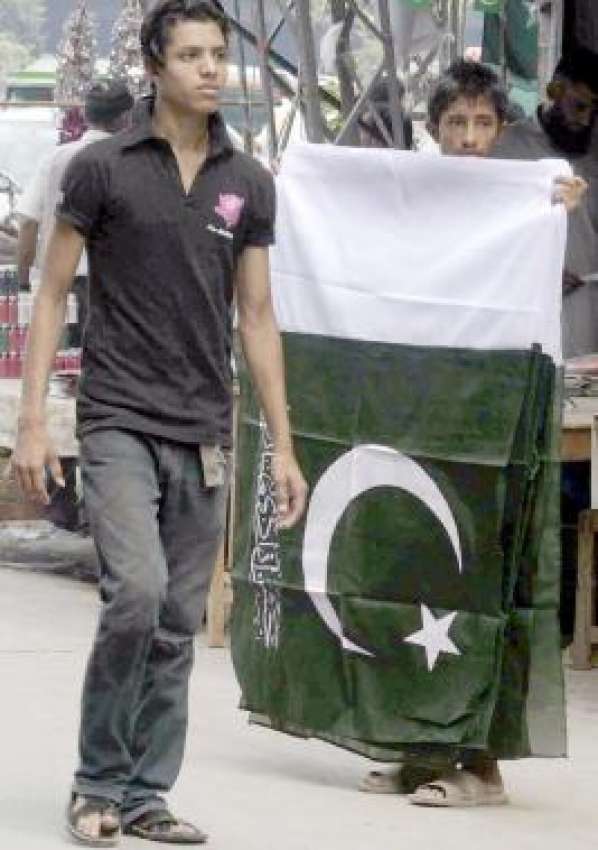 لاہور، یوم آزادی کی مناسبت سے ایک بچہ قومی پرچم خرید رہا ..