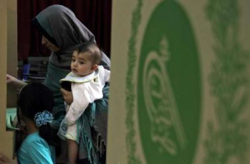 اسلام‌آباد، ایک خاتون اپنے کمسن بچے کو لئے ووٹ کاسٹ رہی ..