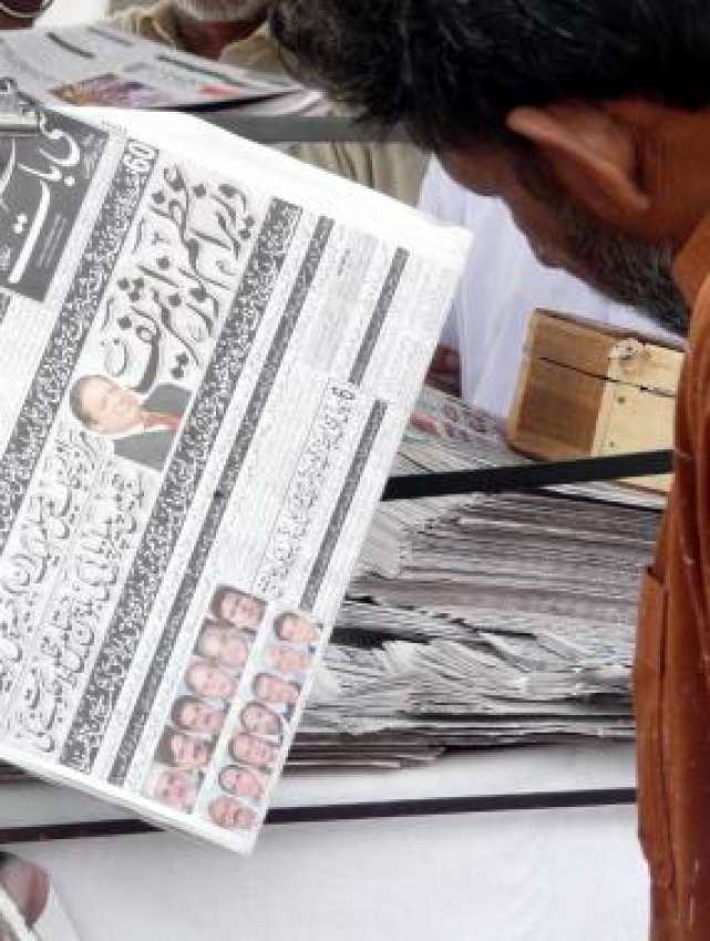 راولپنڈی، ایک شخص‌ اخبار کو سٹال پر انتخابات کے حوالے سے ..