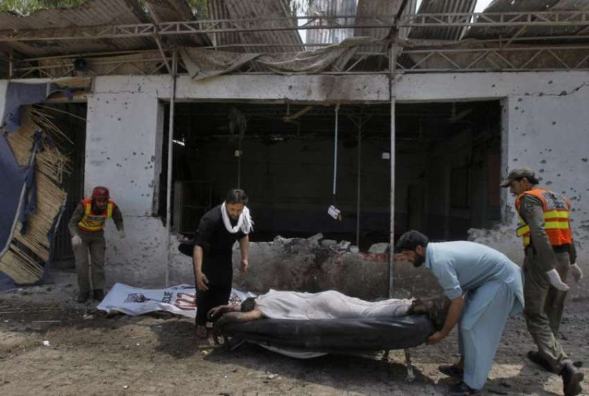 پشاور، امدادی اہلکار خودکش حملہ کے بعد ایک نعش اُٹھا رہے ..