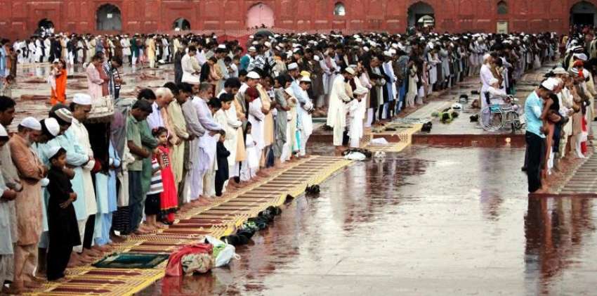 لاہور، شدید بارش میں‌ شہری نماز عید ادا کر رہے ہیں۔ 