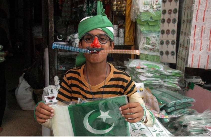 لاہور: جشن آزادی کی تیاریوں میں مصروف ایک بچہ ماسک پہنے اپنی ..