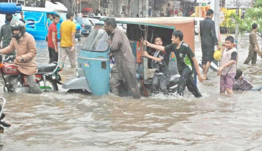 لاہور، بچے بارش کے پانی میں بند ہونے والے رکشے کو باہر نکالنے ..