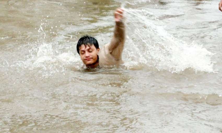 لاہور، شدید بارش سے جمع ہونے والے پانی میں نوجوان تیراکی ..