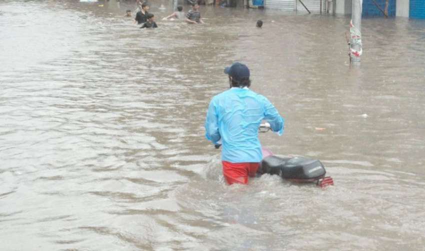لاہور، ایک شخص بارشوں کے بعد کھڑے ہونے والے پانی میں اپنی ..