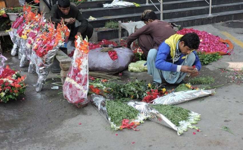لاہور، مال روڈ‌پر ایک شخص پھولوں کے گلدستے تیار کر رہا ہے۔