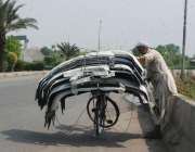 لاہور: ایک محنت کش سائیکل پر گاڑیوں کے بمپر باندھ رہا ہے۔