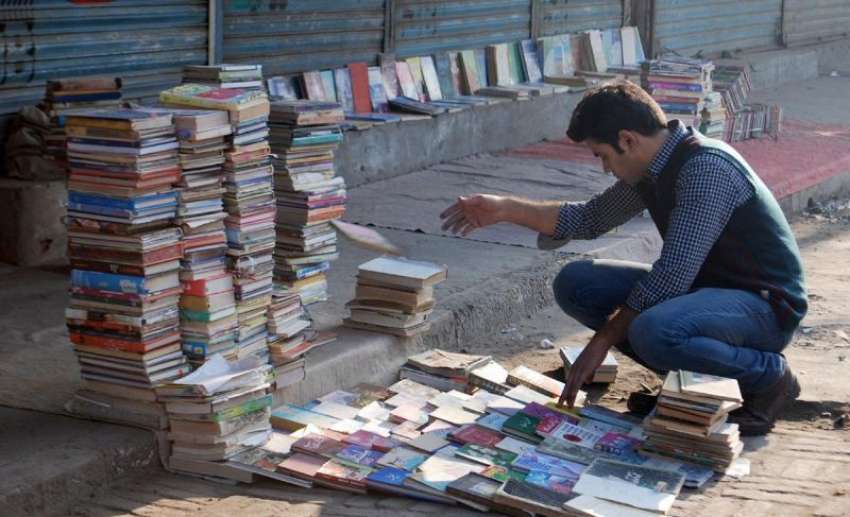 فیصل آباد، ایک طالبعلم سڑک کنارے لگے سٹال سے کتابیں خرید ..