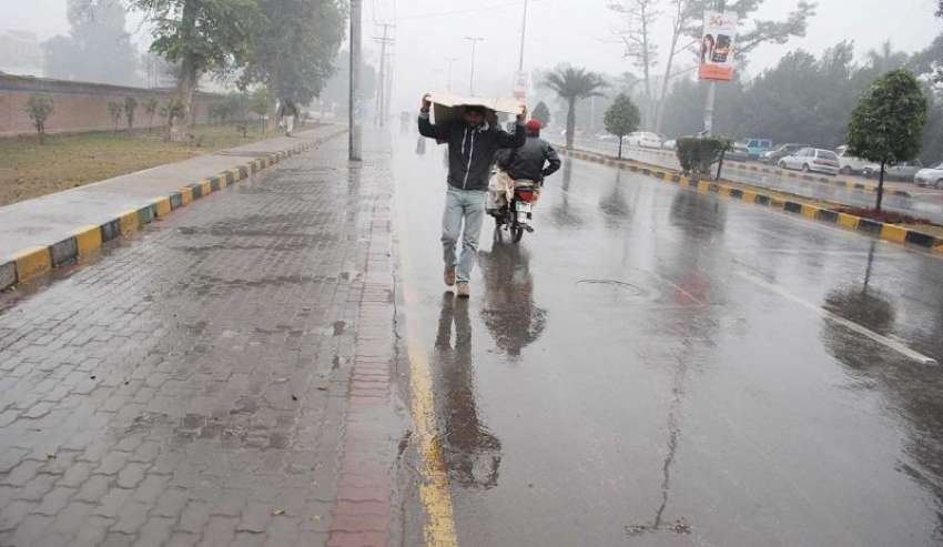 فیصل آباد، موسم سرما کی پہلی بارش کے موقع پر ایک شہری پلاسٹک ..