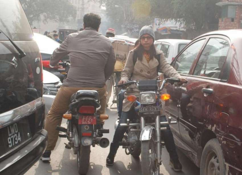 لاہور، ایک موٹر سائیکل سوار خاتون فین روڈ پر ٹریفک جام میں ..