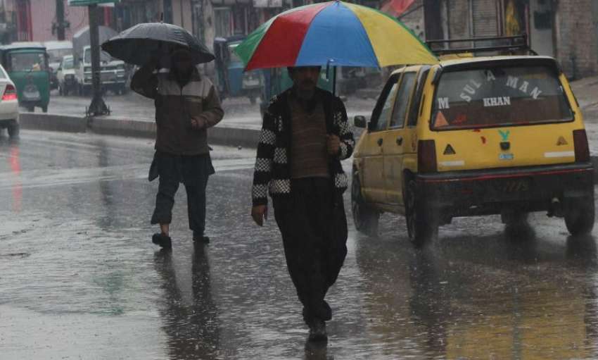 پشاور، شہری شدید بارش میں چھتری کے سائے تلے جا رہے ہیں۔