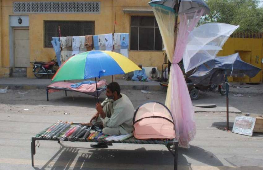 لاہور: ایک شخص چھتریاں اور مچھردانیاں فروخت کرنے کے لیے ..