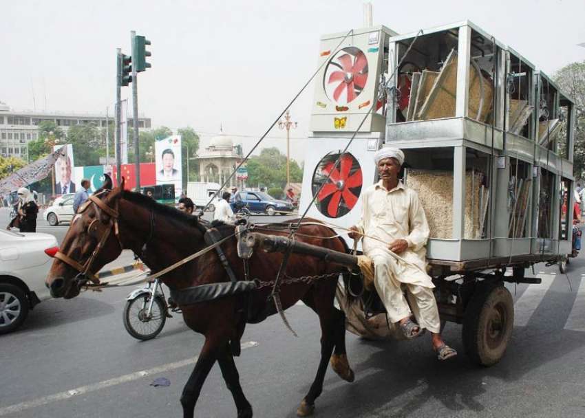 لاہور: ایک شخص ریڑھی پر ائیر کولر رکھے مال روڈ سے گزر رہا ..