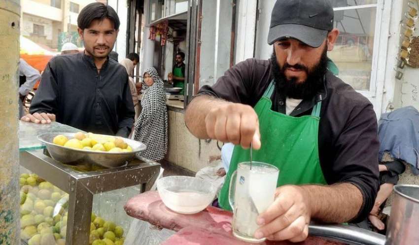 کوئٹہ: میزان چوک پر ایک دکاندار اپنے گاہک کے لیے لیموں کا ..