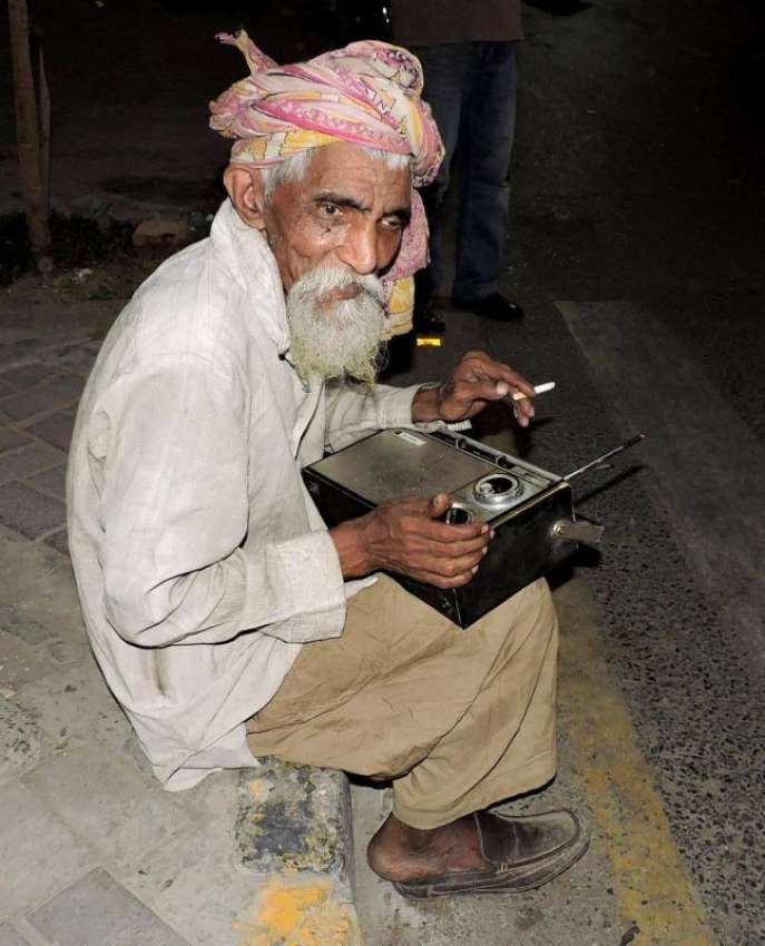لاہور: ایک ضعیف العمر شخص ریگل چوک میں سڑک کنارے بیٹھا ریڈیو ..