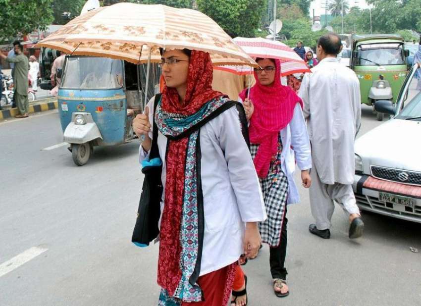 لاہور: طالبات گرمی کی شدت اور دھوپ سے بچنے کے لیے چھتری تانے ..