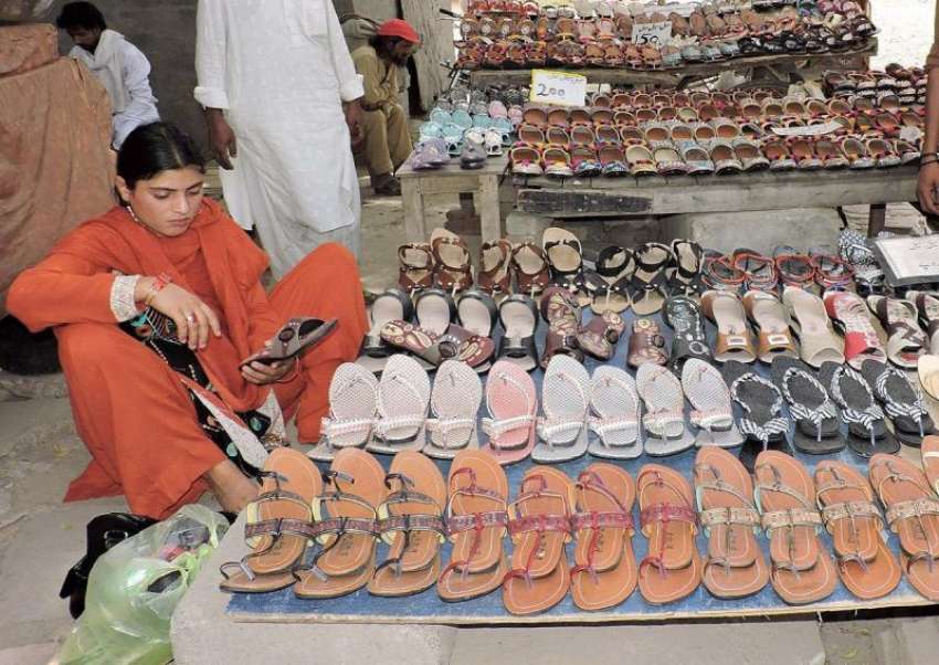لاہور: ایک خاتون بادشاہی مسجد کے قریب لگے سٹال سے جوتا پسند ..