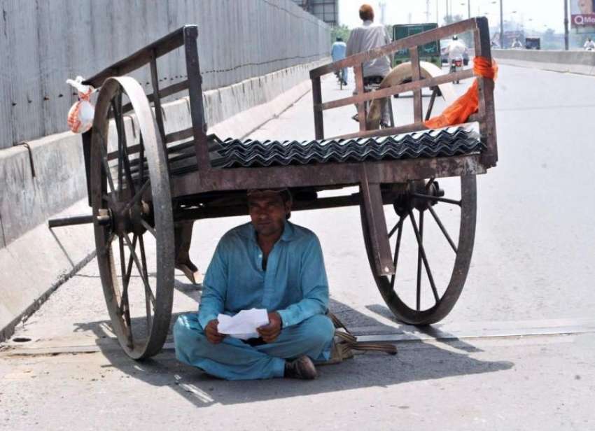 لاہور: ایک محنت کشی شدید گرمی کے باعث ریڑھی کے نیچے چھاؤں ..