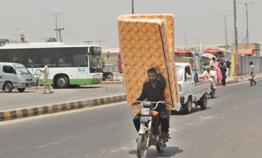 لاہور: ایک شخص موٹر سائیکل پر میٹرس لیجا رہا ہے۔