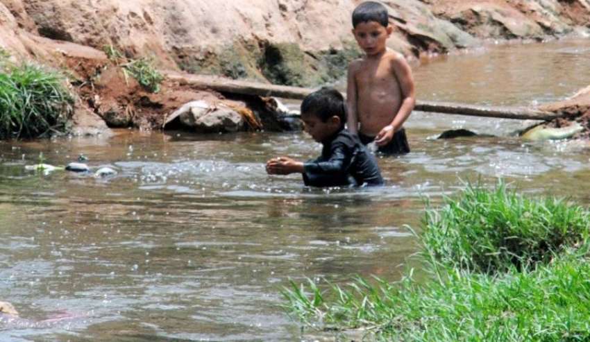 راولپنڈی: گرمی کی شدت کم کرنے کے لیے بچے نالے میں نہا رہے ..