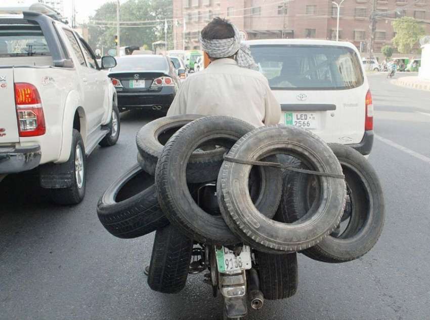 لاہور: ایک شخص موٹر سائیکل پر پرانے ٹائر رکھے جا رہا ہے۔