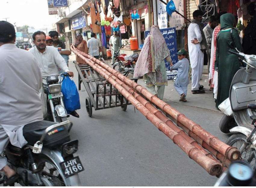 لاہور: ایک محنت کش ہتھ ریڑھی پر بانس رکھے جا رہا ہے۔
