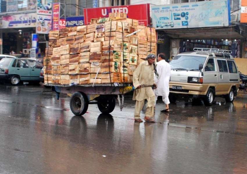 راولپنڈی: لیاقت روڈ پر بارش کے بعد ایک مزدور اپنی منزل کی ..