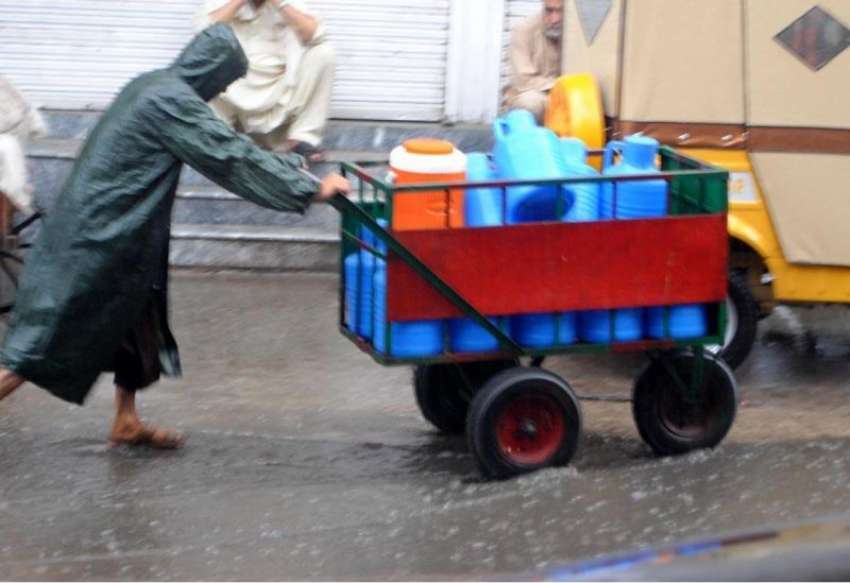 راولپنڈی: لال حویلی روڈ پر ایک مزدور بارش کے دوران دکانداروں ..