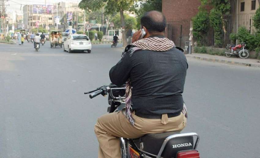 لاہور: ایک موٹر سائیکل سوار پولیس اہلکار دوران ڈرائیونگ ..