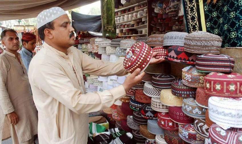 لاہور: ایک شخص ٹوپیاں فروخت کرنے کے لیے ترتیب سے رکھ رہا ..