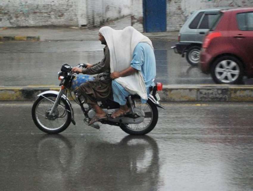 لاہور: شہر میں ہونے والی تیز بارش کے دوران موٹر سائیکل سوار ..